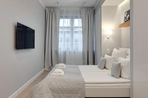 a white bedroom with a large bed with white pillows at Downtown Apartments Seaside Rezydencja Marina in Gdańsk
