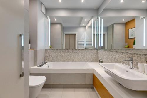 a bathroom with two sinks and a tub and a toilet at Downtown Apartments Seaside Rezydencja Marina in Gdańsk