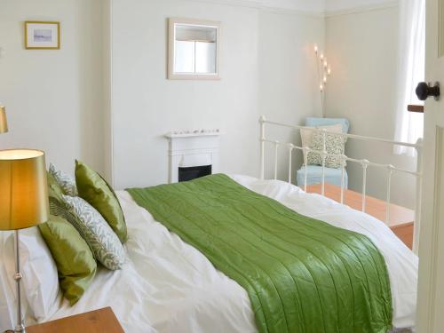 a bedroom with a bed with a green comforter at Tregatta Terrace in Tintagel