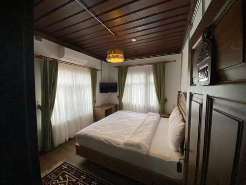 a bedroom with a bed and two windows at Ziyagil Konağı in Amasya