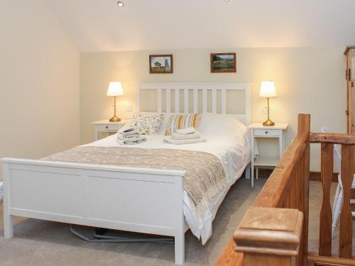 um quarto com uma cama branca com duas mesas de cabeceira em The Barn em Tickton