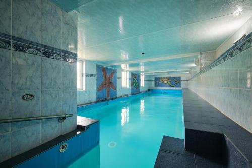 - une piscine d'eau bleue dans un bâtiment dans l'établissement Dobrzyński Resort Hotel Nefryt, à Świeradów-Zdrój