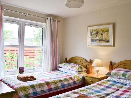 two beds in a room with a window at Glenrothay in Aviemore