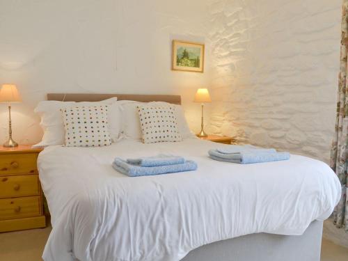 a bedroom with a white bed with towels on it at Dovecote-tnq in Camelford