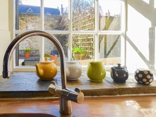 um lavatório de cozinha com um monte de vasos sentados em frente a uma janela em Forge View Cottage em Thornton Dale