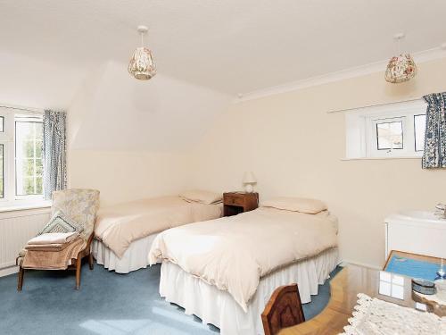 a bedroom with two beds and a chair in it at Shaws Cottage in Thornton Dale