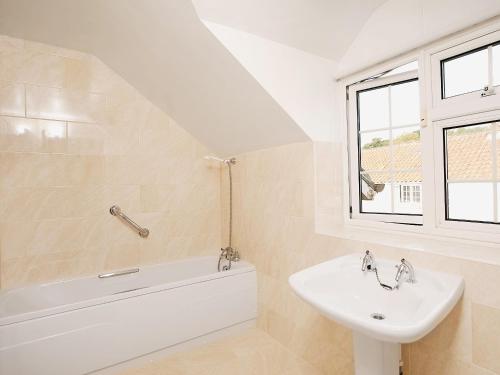 a white bathroom with a sink and a bath tub at Shaws Cottage in Thornton Dale