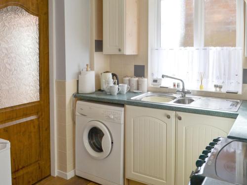 a kitchen with a washing machine and a sink at Seashore Hideaway in Newbiggin-by-the-Sea
