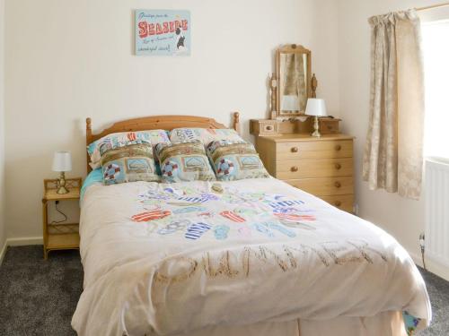 a bedroom with a bed and a dresser with a mirror at Seashore Hideaway in Newbiggin-by-the-Sea