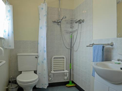 y baño con ducha, aseo y lavamanos. en Ty Main Cottage, en Newborough