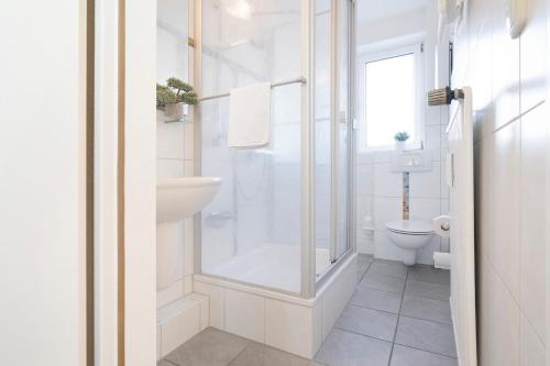 uma casa de banho branca com um chuveiro e um WC. em Ferienwohnung 18 mit Balkon im Haus Achtern Diek em Grömitz