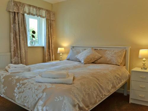 a bedroom with a bed with two towels on it at Ty Main Cottage in Newborough