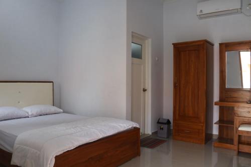 a bedroom with a bed and a wooden dresser at Aluky Hotel in Majalengka