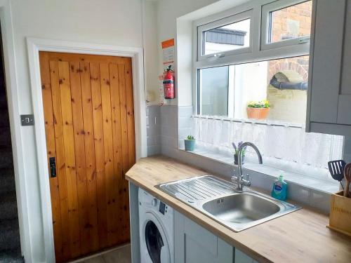 a kitchen with a sink and a washing machine at Amberley Cottage in Alfreton