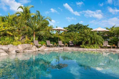 a pool at a resort with chairs and umbrellas at Habitation Saint Charles - Hôtel de Charme & Spa in Petit-Bourg