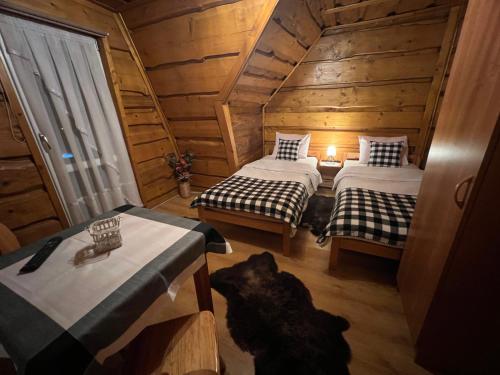 a room with two beds in a wooden cabin at Na Poddaszu - apartament na wyłączność in Kluszkowce