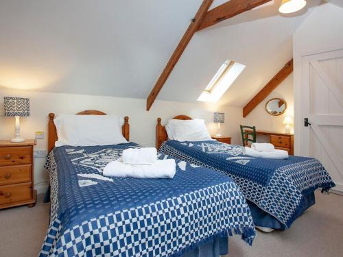 a bedroom with two beds with blue and white sheets at The Roundhouse - Tbe in Crackington Haven