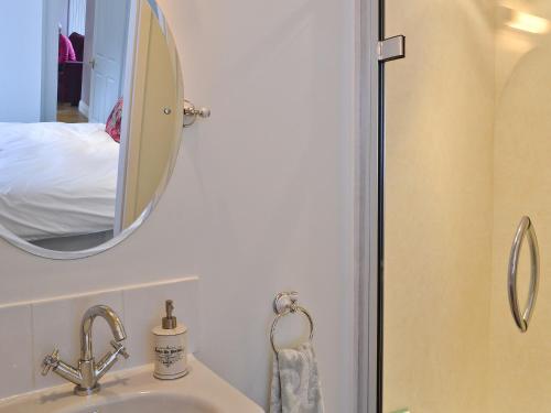 a bathroom with a sink and a mirror and a bed at Roseburn Cottage in Moffat