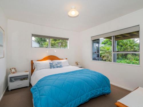 een slaapkamer met een groot bed en 2 ramen bij 12 on Hilldale - Kuaotunu Holiday Unit in Whitianga