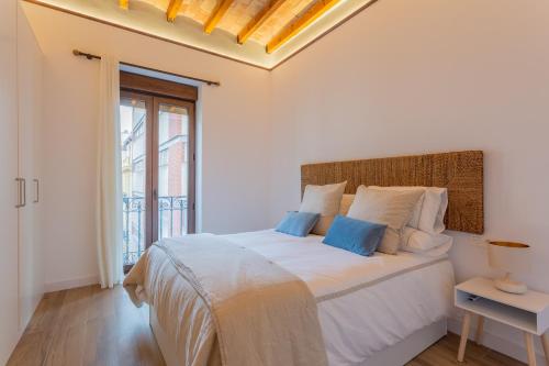 a white bedroom with a large bed and a window at Apartamento Cetti Meriem in Granada