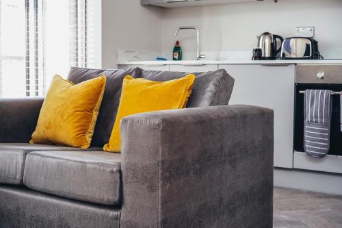 a brown couch with yellow pillows in a kitchen at The Stay Company, Whitefriars House in Nottingham