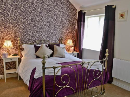 a bedroom with a bed with a purple comforter at Wheatsheaf Cottage in Nun Monkton
