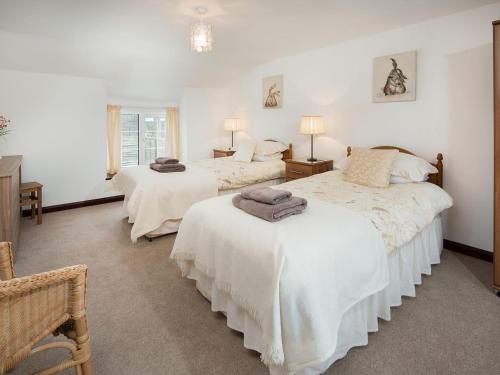 um quarto com 2 camas e lençóis brancos em Seascape em Craster