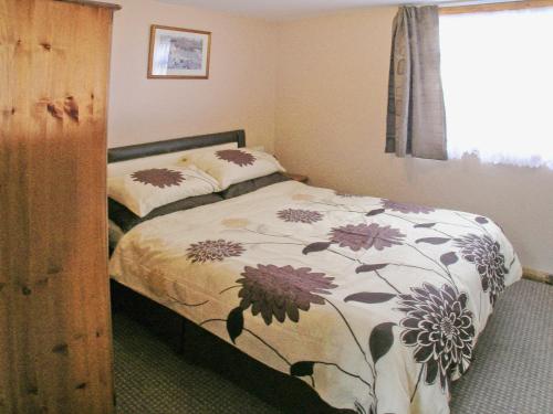 a bedroom with a bed with a floral comforter at Summer Time in Brundall