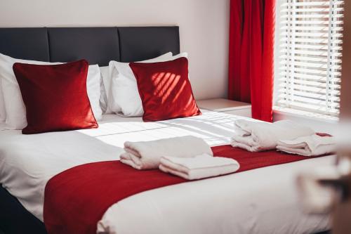 a bed with towels on it with red pillows at The Stay Company, Whitefriars House in Nottingham
