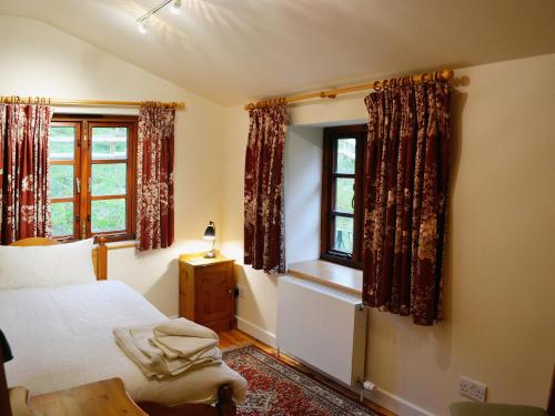 a bedroom with a bed and two windows at Heol Llygoden in Cathedine