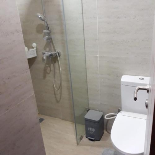 a bathroom with a shower with a toilet and a trash can at The Accent Apartemen in Jurangmanggu