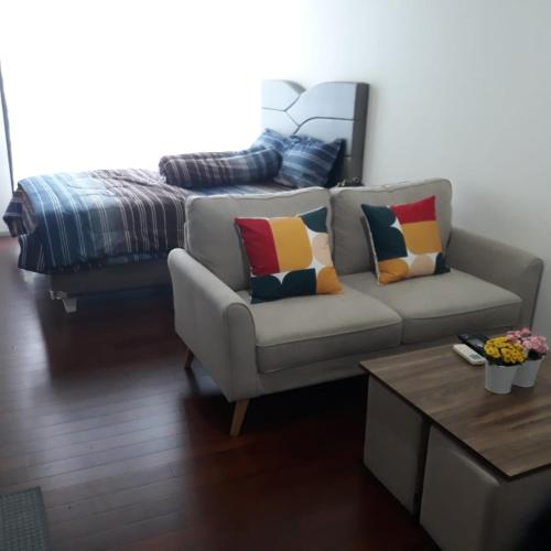 a living room with a couch and a bed at The Accent Apartemen in Jurangmanggu