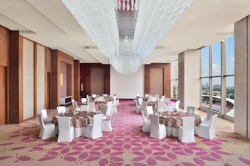 a banquet hall with tables and white chairs and a chandelier at Courtyard by Marriott Navi Mumbai in Navi Mumbai