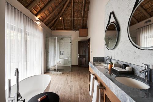 a bathroom with two sinks and a large mirror at Letamo at Qwabi Private Game Reserve by NEWMARK in Bela-Bela