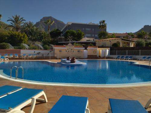 a swimming pool in a resort with blue chairs at Miraverde Bright studio with Great Views in Adeje
