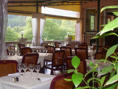 サン・ジャン・デュ・ガルにあるLogis Hotel Restaurant la Corniche des Cevennesの白いテーブルと椅子とガラスを用意したレストラン