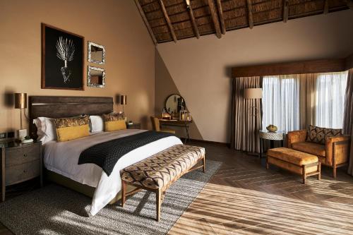 - une chambre avec un lit, un canapé et une chaise dans l'établissement Letamo at Qwabi Private Game Reserve by NEWMARK, à Bela-Bela