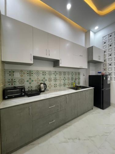La cuisine est équipée de placards blancs et d'un réfrigérateur noir. dans l'établissement HO GIA AN Home - King Room, à Ấp Lợi Ðủ