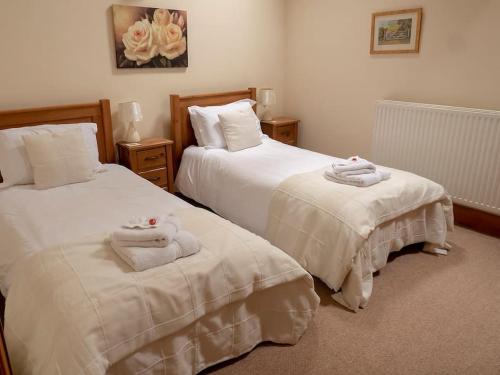 two beds with towels on them in a bedroom at Wheelhouse Cottage . A brick-built barn conversion in Thirsk