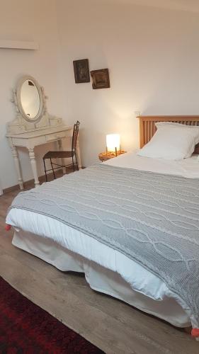 une chambre avec un lit avec une table et un miroir dans l'établissement charmant logement à la campagne, à Gazaupouy