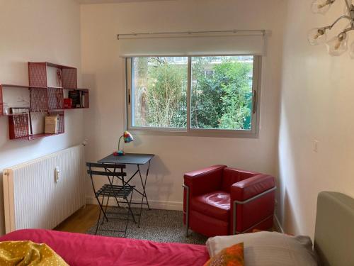 a living room with a red chair and a table at Vue sur jardin, 3 pièces in Paris