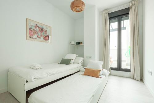 a white room with two beds and a window at Tejares Sevilla Luxury Penthouse en Triana - gran terraza, piscina & parking privados in Seville