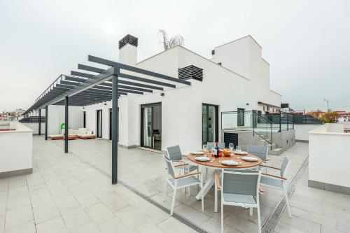 a patio with a table and chairs on a roof at Tejares Sevilla Luxury Penthouse en Triana - gran terraza, piscina & parking privados in Seville