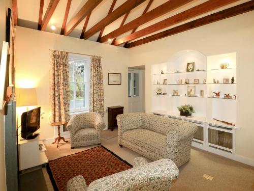 a living room with two chairs and a tv at Gardener's Cottage in Skirling