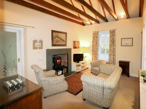 a living room with two chairs and a fireplace at Gardener's Cottage in Skirling