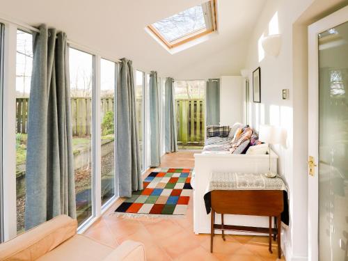 a room with windows and a bed and a table at Gardener's Cottage in Skirling