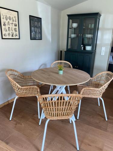 a dining room table with rattan chairs and a cabinet at Gemütliches Ferienhaus an der Ostsee mit Kamin in Rerik