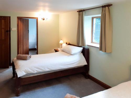 een slaapkamer met een bed en een raam bij Meadowside Cottage in Calton