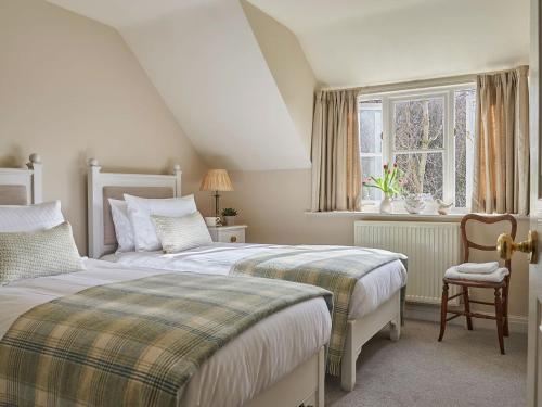 a bedroom with two beds and a chair and a window at Hungate Garden Cottage in Pickering
