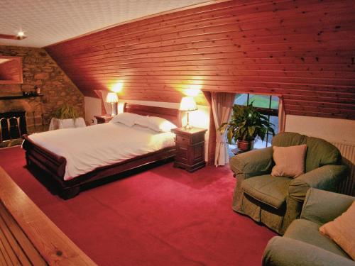 um quarto com uma cama e duas cadeiras num quarto em The Coach House em Birnam